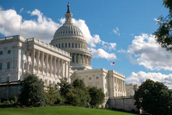 US Capitol building with white dome, columns, and American flag on clear blue sky day