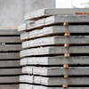 Stacked concrete construction panels with wooden spacers in industrial setting