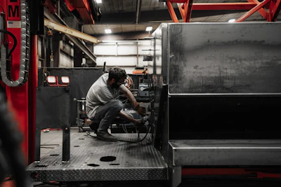 Technician working on machinery in dimly lit industrial workshop