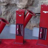 Three red industrial machines with angled metal components on gray stone surface