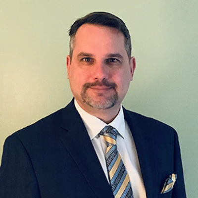 Professional man in navy suit and striped tie against neutral background