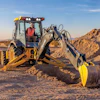 Yellow John Deere backhoe digging trench in arid desert construction site