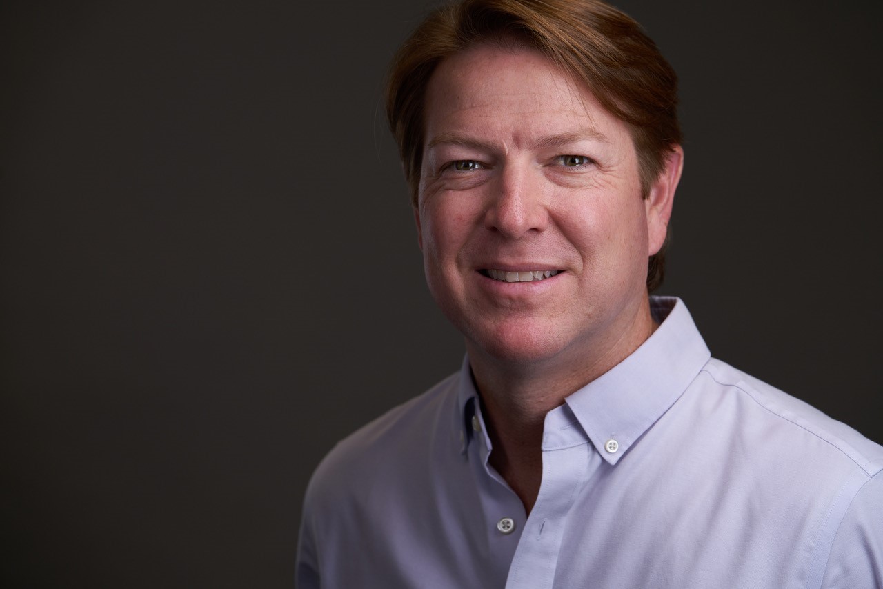 Professional headshot of a smiling man in a white button-down shirt Headshot