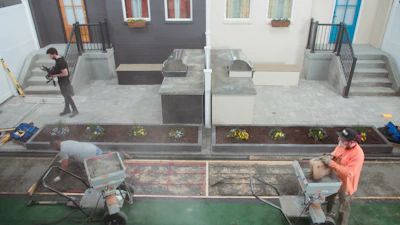 Construction workers installing pavers and landscaping near residential buildings