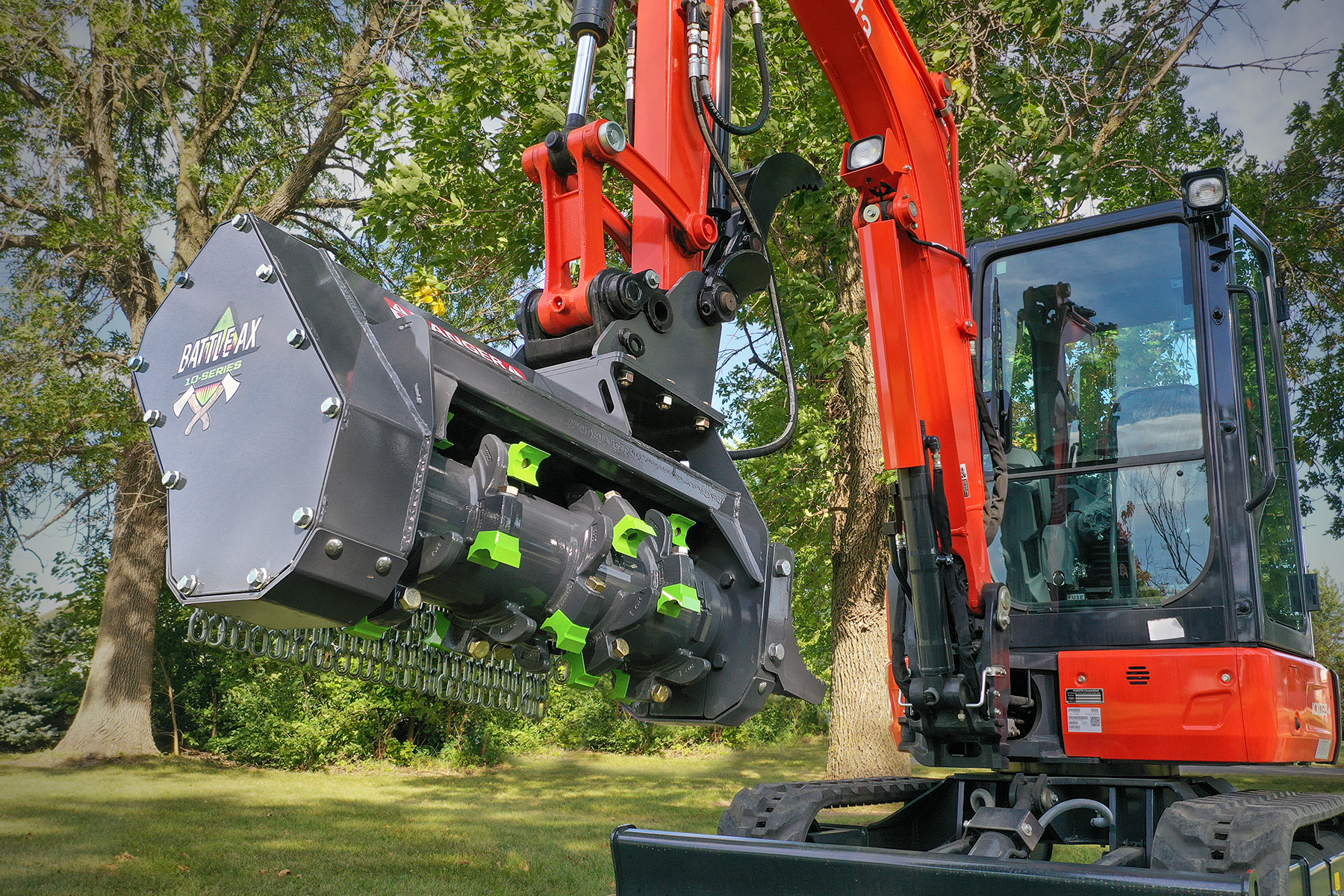 Red compact excavator with forestry mulching attachment clearing vegetation near trees