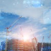 Construction site with cranes and digital technology interface overlay at sunset