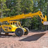 Yellow Pettibone telehandler on dirt path surrounded by trees