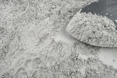 Gray powdery substance spread across surface with mound of dry material