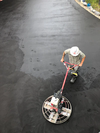 Construction worker using power trowel to smooth wet concrete surface