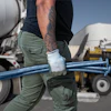 Construction worker carrying blue metal pipes near concrete mixer truck