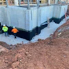 Construction site with concrete foundation walls and workers in safety vests
