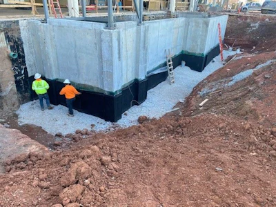 Construction site with concrete foundation walls and workers in safety vests