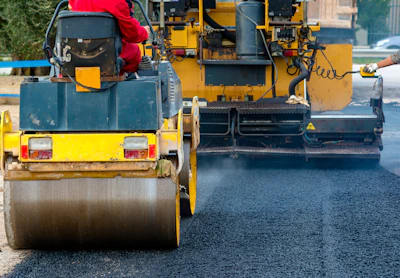 Road roller compacting fresh asphalt during highway construction
