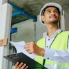 Construction worker in white hard hat and yellow safety vest reviewing documents on site