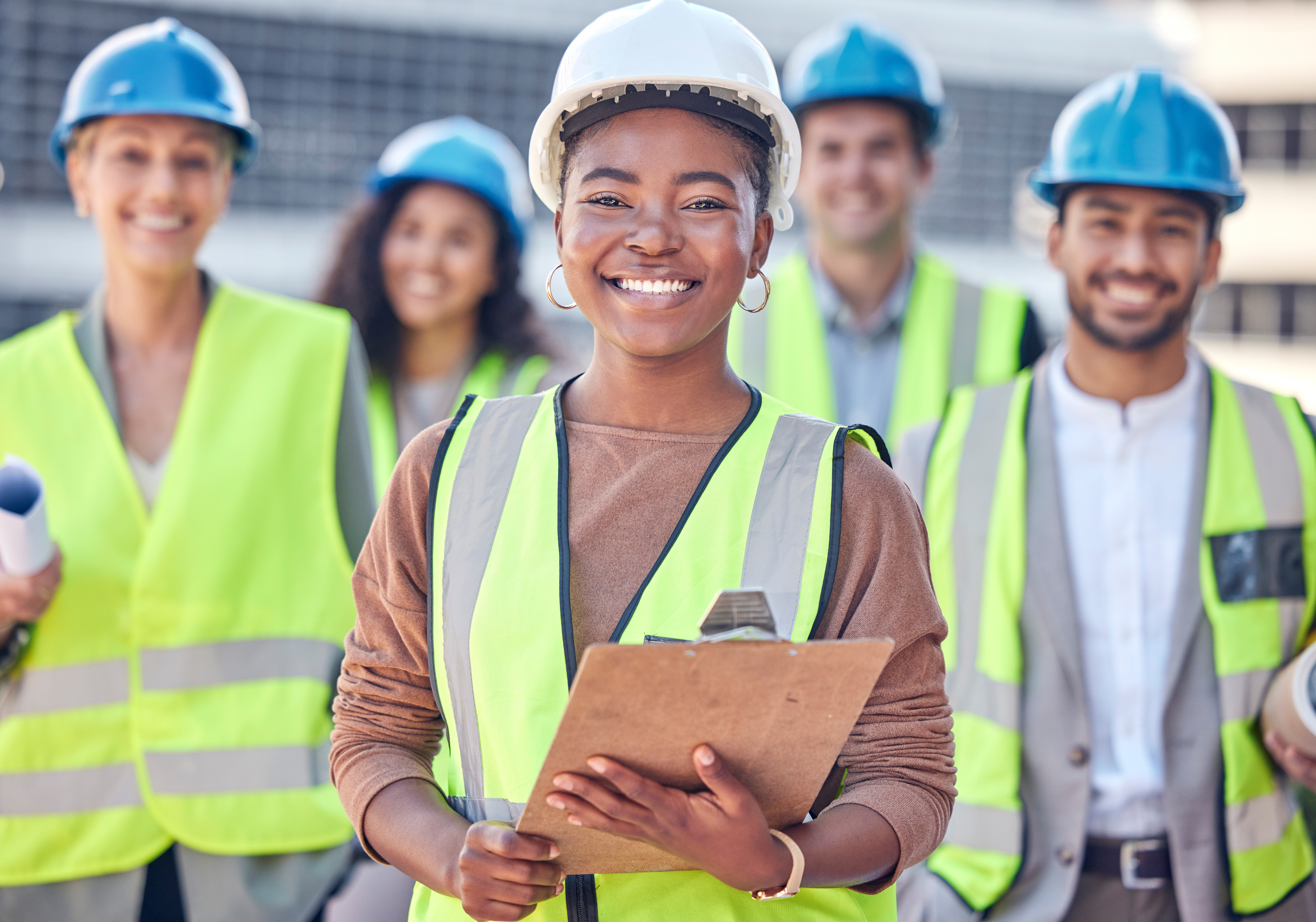 Smiling construction team in safety vests and hard hats at worksite