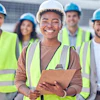 Smiling construction team in safety vests and hard hats at worksite