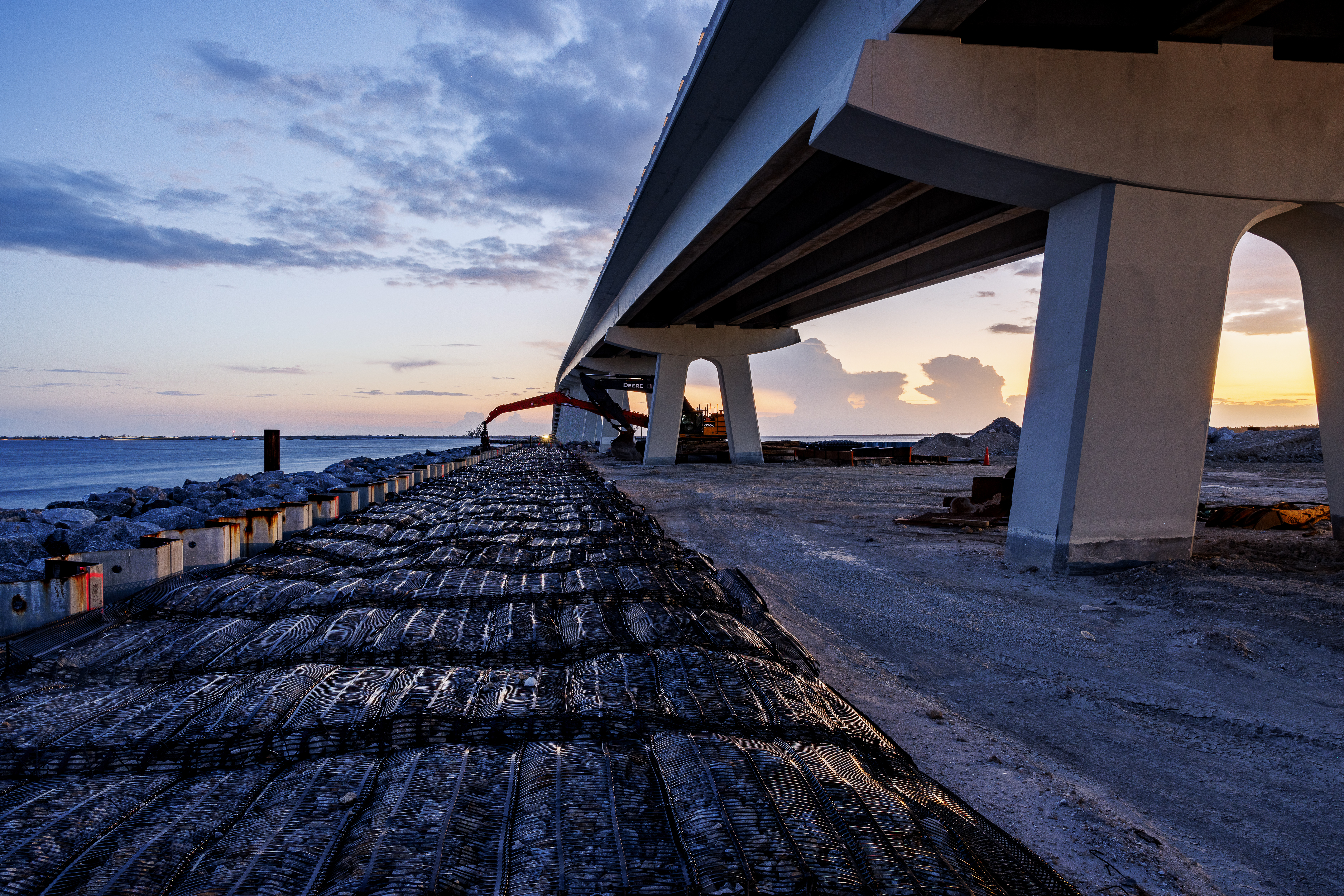 Concrete highway bridge over rocky coastline at sunset with dramatic sky
