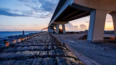 Concrete highway bridge over rocky coastline at sunset with dramatic sky