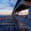 Concrete highway bridge over rocky coastline at sunset with dramatic sky