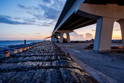 Concrete highway bridge over rocky coastline at sunset with dramatic sky