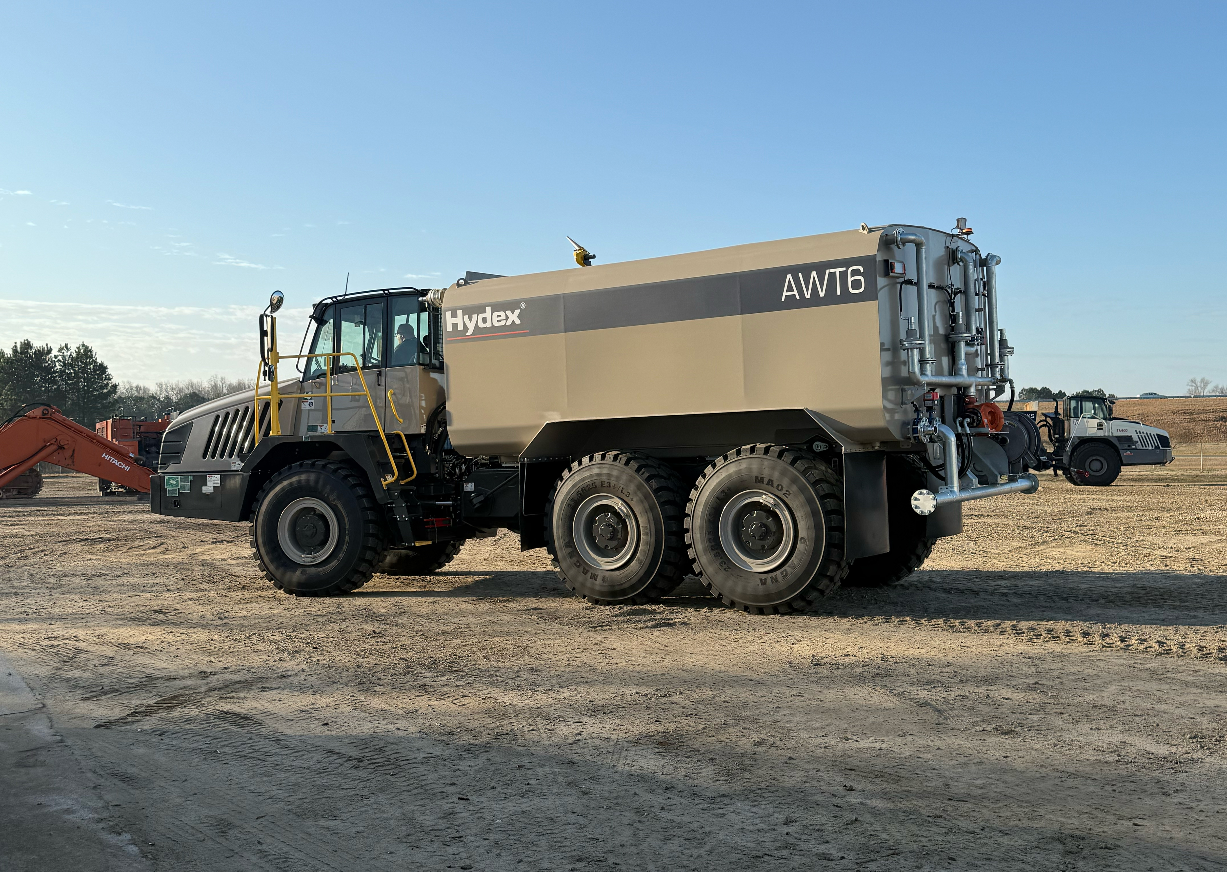 Large tan Hydex AWT6 articulated water truck on dirt construction site