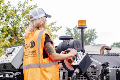 Construction worker operating heavy machinery wearing high-visibility safety vest