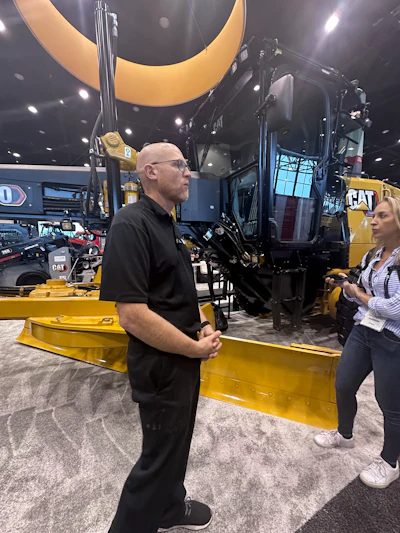 Yellow Caterpillar construction machine at industrial trade show with attendees