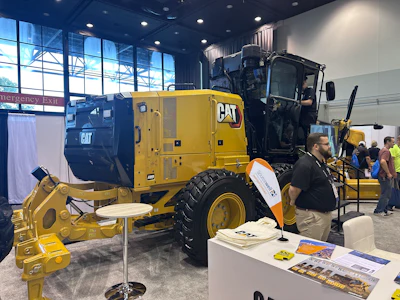 Yellow Caterpillar motor grader on display at industrial equipment trade show