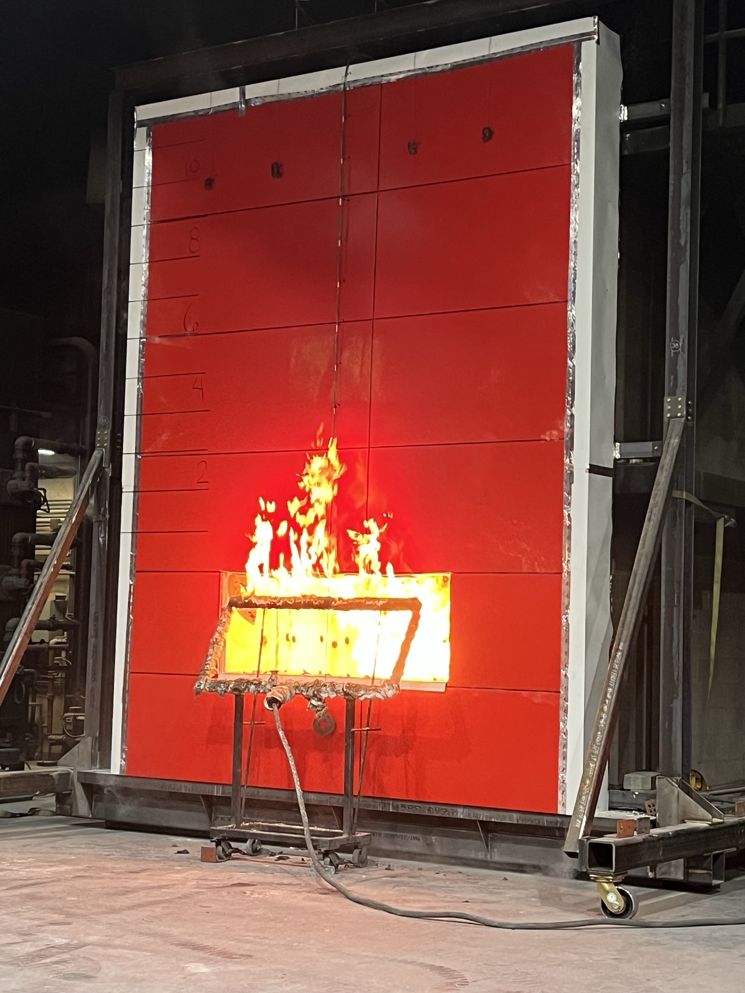 Fire resistance test with flames burning on red industrial testing panel