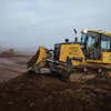 Yellow John Deere bulldozer moving earth on a construction site at dawn