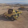 Yellow mining haul truck moving earth in desert quarry with mountain landscape