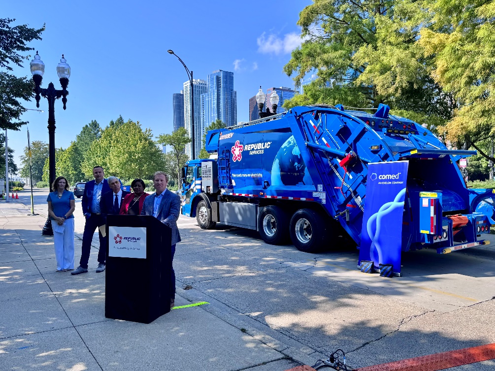 Blue Republic Services garbage truck at press conference with city skyline