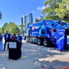 Blue Republic Services garbage truck at press conference with city skyline