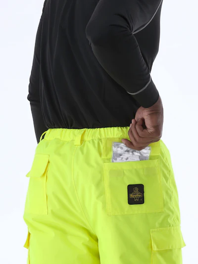 Neon yellow cargo work pants with black patch logo on back pocket, shown with black long-sleeve shirt