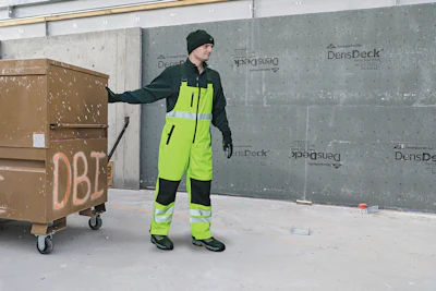 Construction worker in bright safety vest near materials container at building site