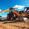 Orange and yellow backhoe loader working on sandy terrain with blue sky and clouds