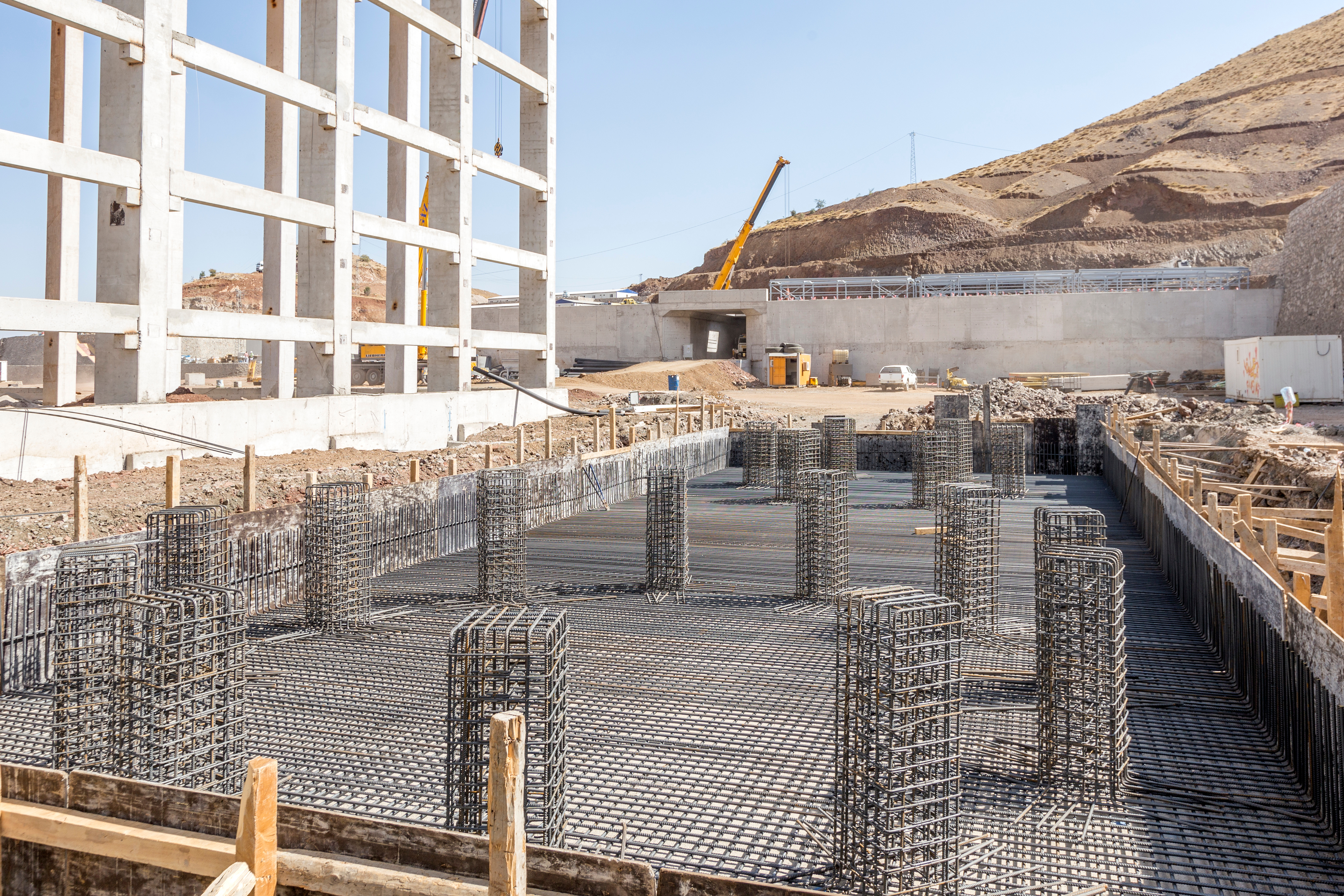 Construction site with steel reinforcement grid and concrete foundation in arid landscape
