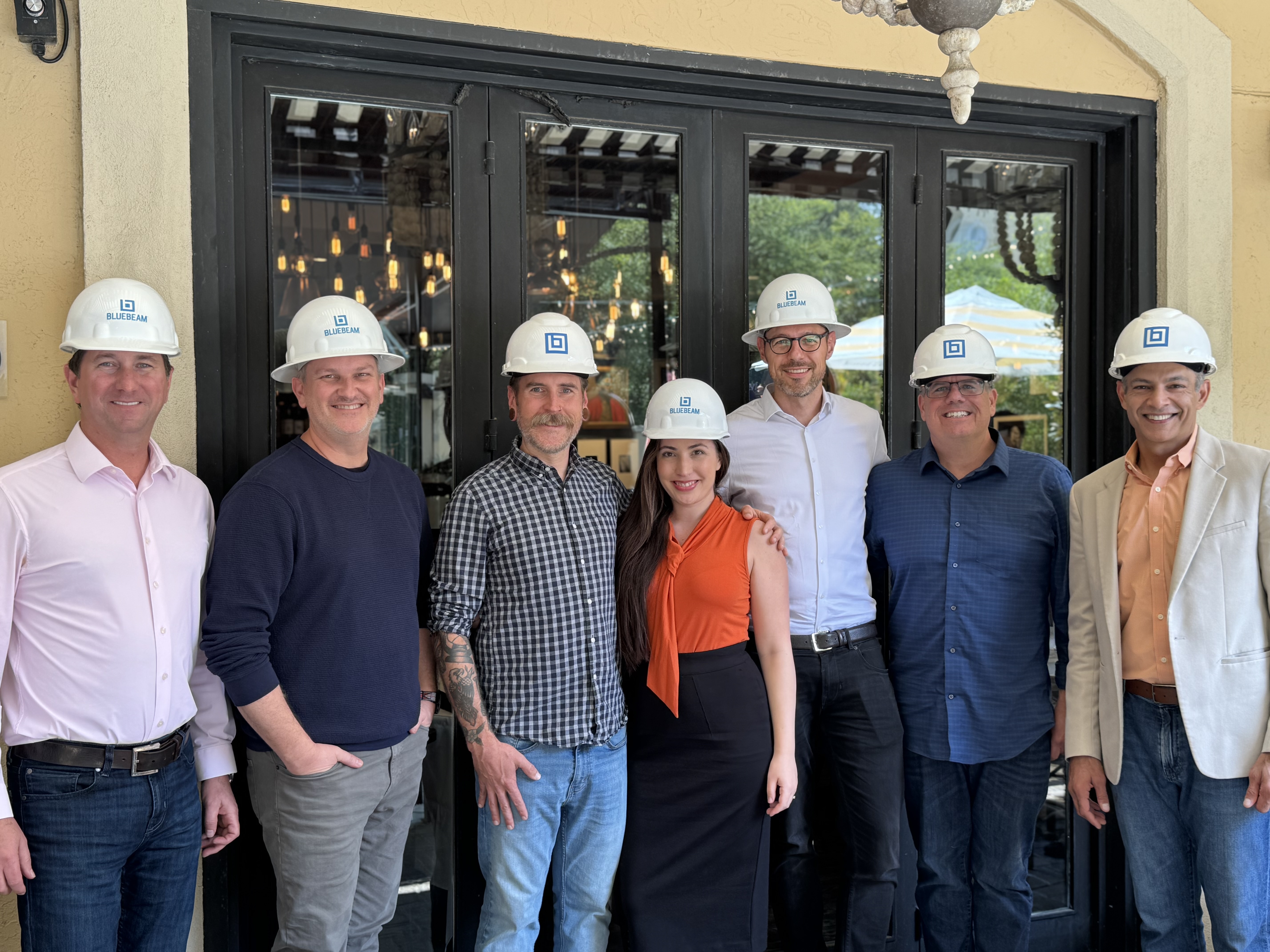 Group of six construction professionals wearing white hard hats standing together