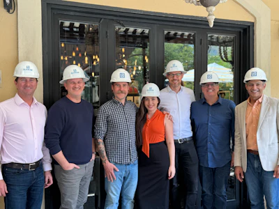 Group of six construction professionals wearing white hard hats standing together