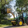Green John Deere tractor parked on dirt road surrounded by trees