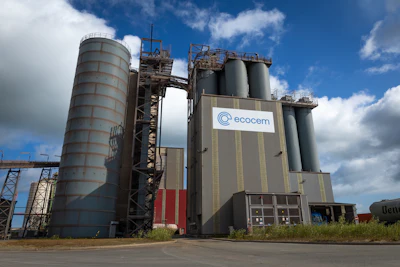 Industrial cement manufacturing plant with large silos and Ecocem logo