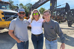 Three professionals standing near Volvo excavators at construction equipment site