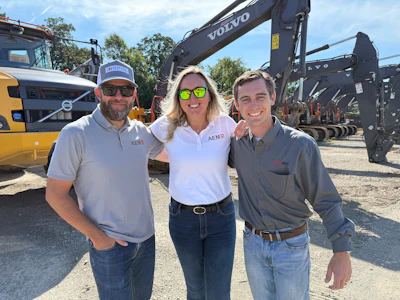 Three professionals standing near Volvo excavators at construction equipment site