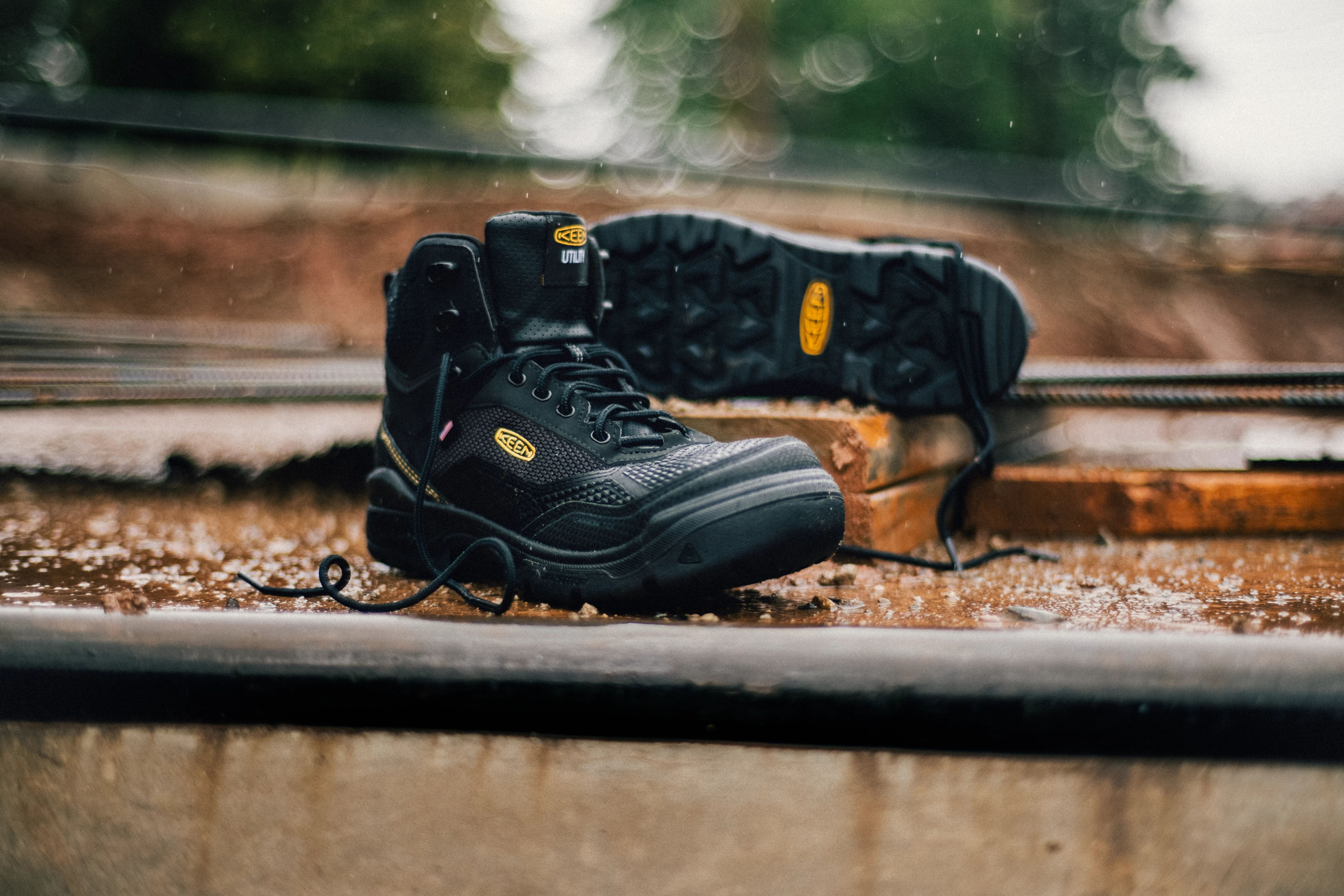 Black Keen work boot with yellow accents on weathered wooden surface