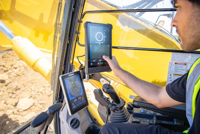 Construction worker operating yellow excavator with digital touchscreen displays