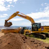 Yellow Komatsu excavator loading soil at construction site with dump truck