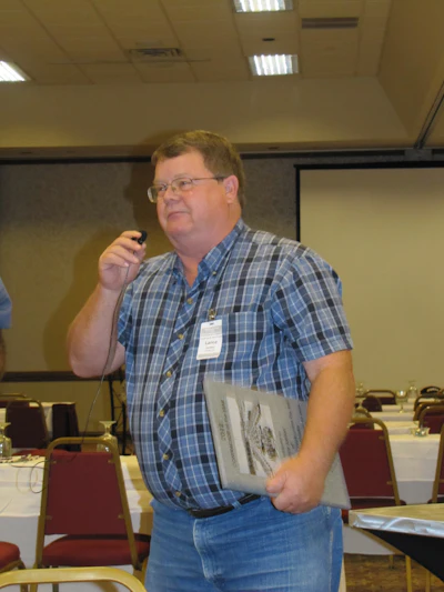 Presenter speaking at conference with microphone and document in conference room