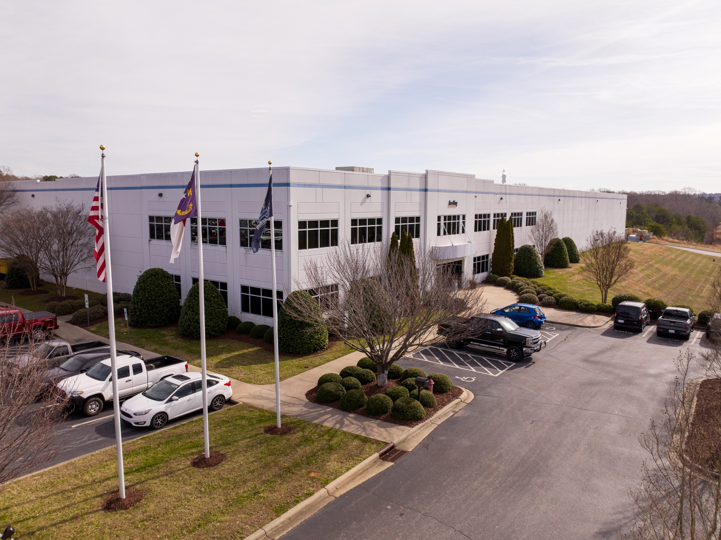 Corporate office building with flags, landscaped parking area and parked vehicles