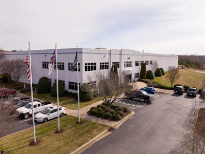 Corporate office building with flags, landscaped parking area and parked vehicles