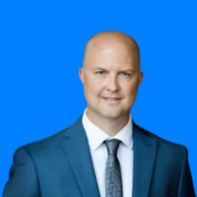 Professional man in blue suit and tie against bright blue background